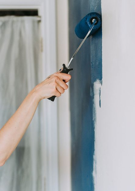 A closeup shot of a person using paint rollers with the color blue